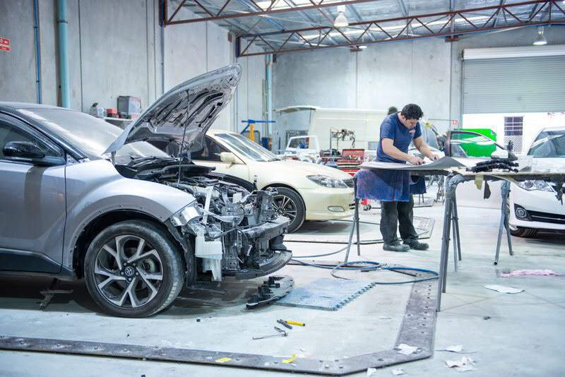 Panel beaters repairing collision damage in the Aarkay Motors smash repair workshop